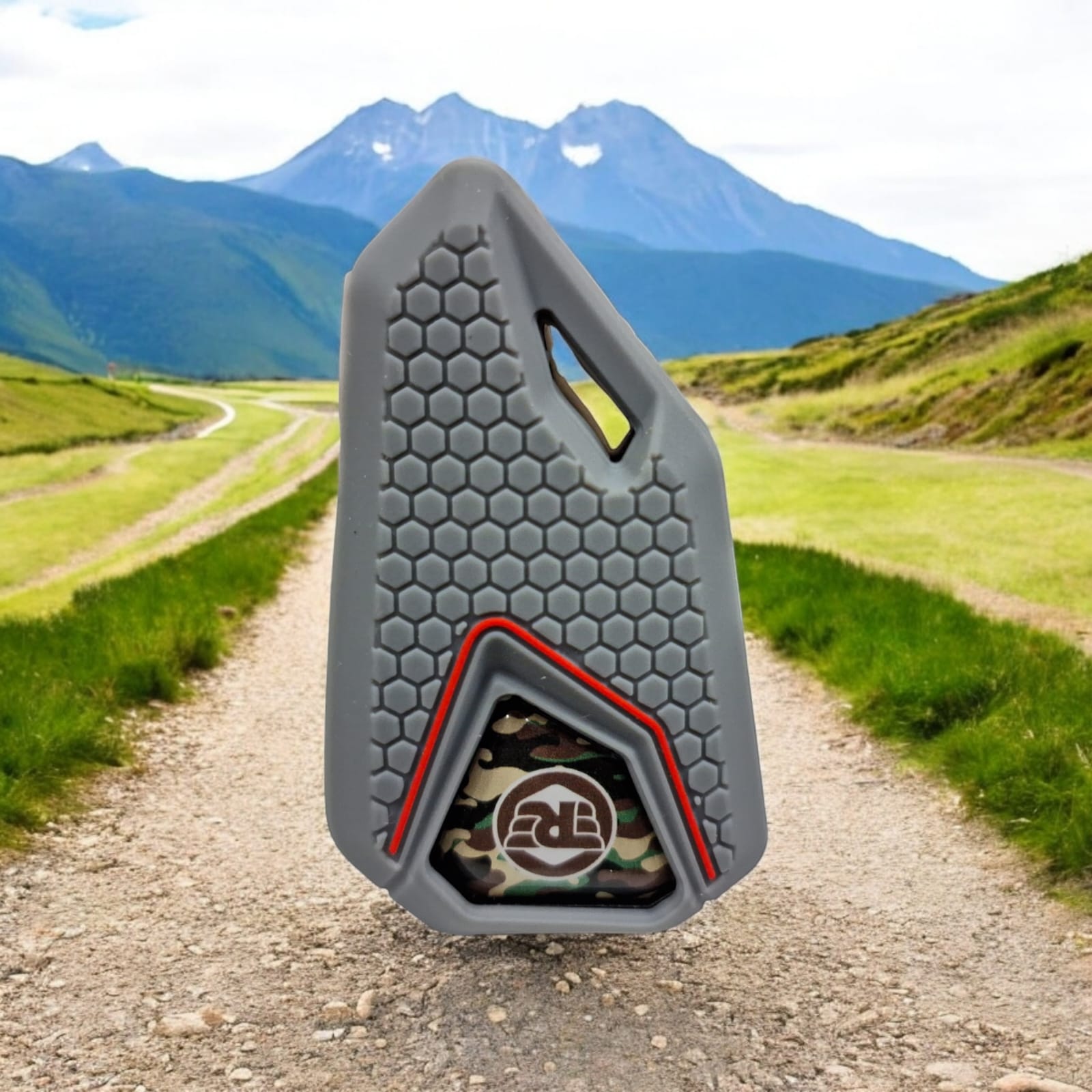 A camouflage-patterned silicone key cover for Royal Enfield motorcycles displayed against a scenic background.